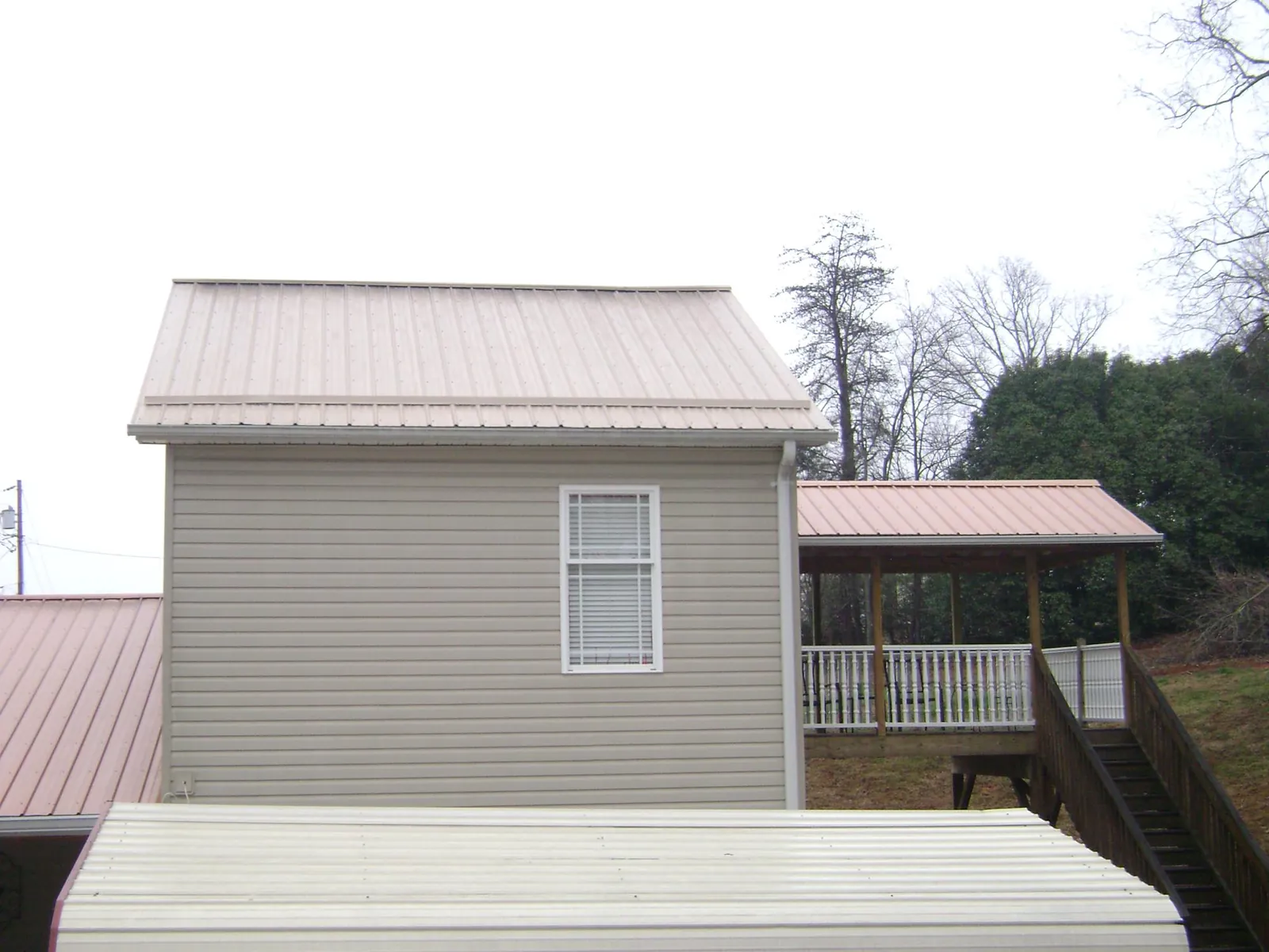 Tan metal roofs on a two story addition and attached porch, from a Roof Replacement job in Millersburg