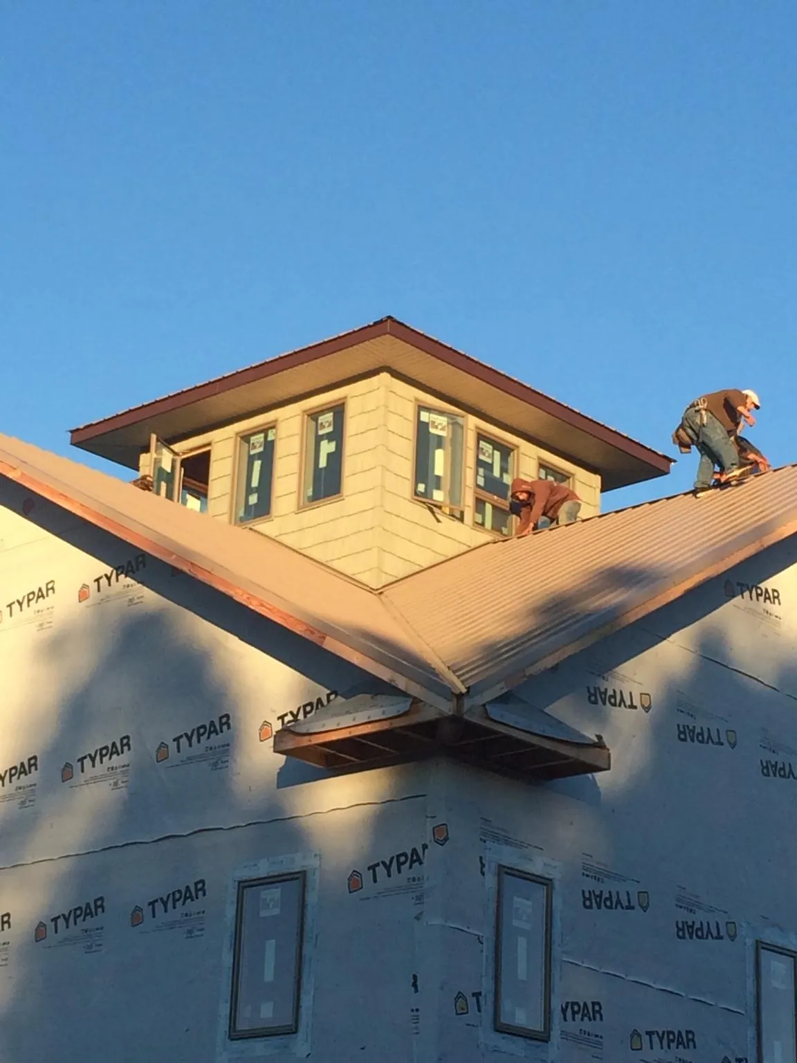 Roofers working around a rooftop cupola on a new metal roof at sunset — Roof Waterproofing in Millersburg by Roofing Brothers